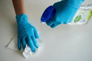 manos con guantes de latex limpiando superficie