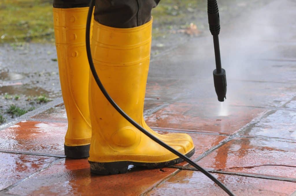 Persona limpiando con botas de goma